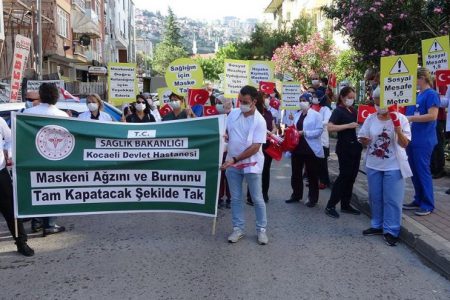 Sağlık çalışanları, maske ve sosyal mesafeye dikkat çekmek için yürüdü